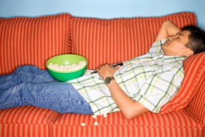 Dca, ragazzo steso sul divano con ciotola di pop corn