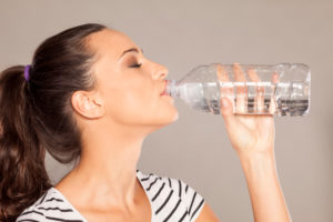 Donna beve acqua direttamente da una bottiglietta