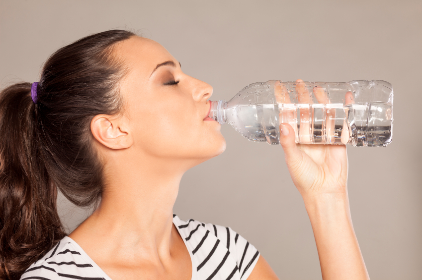 Donna di profilo che beve da una bottiglietta d'acqua con gli occhi chiusi; concept: consigli
