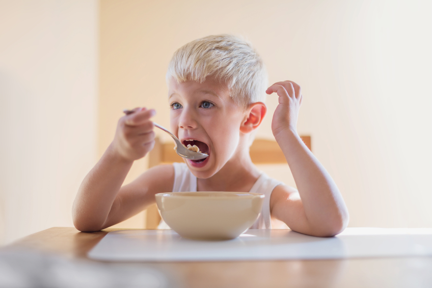 Bambino che mangia una cucchiaiata di cereali