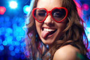 Ritratto di una ragazza che indossa occhiali a forma di cuore che mostra giocosamente la sua lingua