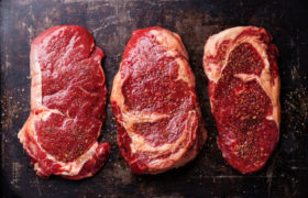 Three cuts of Raw fresh meat Steaks and seasonings on dark backg carne rossa
