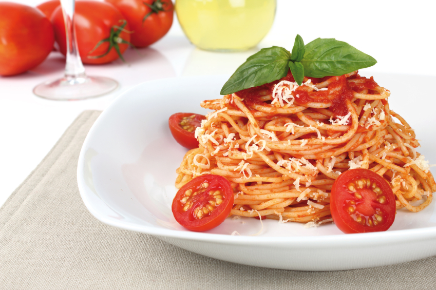 Piatto di spaghetti al pomodoro, con basilico, pomodorini e formaggio
