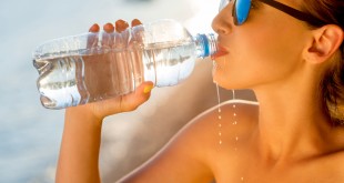acqua minerale Woman drinking water from transparent bottle on the beach