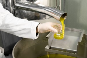 Operatore con camice e guanti preleva un campione di olio extravergine di oliva per analisi o controlli