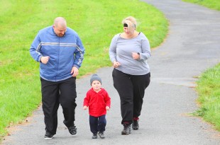 Overweight parents with her son running together.
