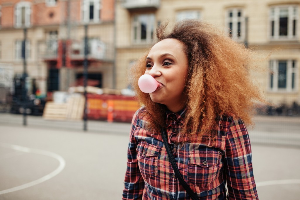 Donna che fa il palloncino con la gomma da masticare; concept: chewing gum