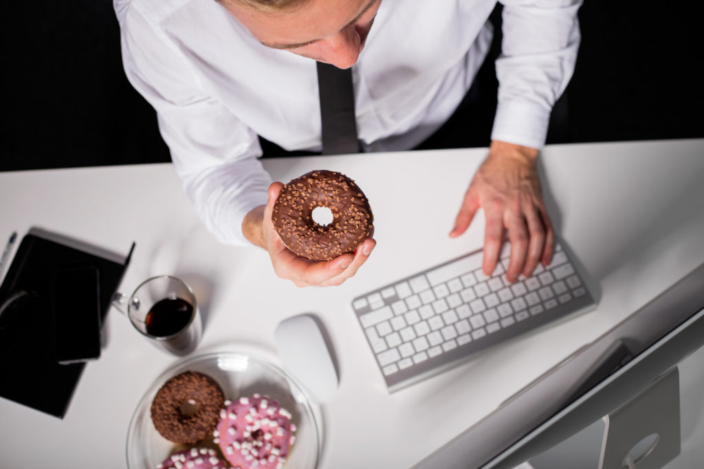 Man at the office eating donuts junk food