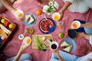 Alcune persone fanno un picnic su una tovaglia a quadretti; concept: estate, pranzo al sacco