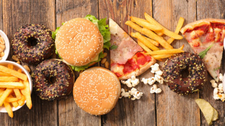 Alimenti poco sani: patatine fritte, hamburger da fast food, pizza, pop corn, donut al cioccolato