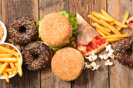 Alimenti poco sani: patatine fritte, hamburger da fast food, pizza, pop corn, donut al cioccolato