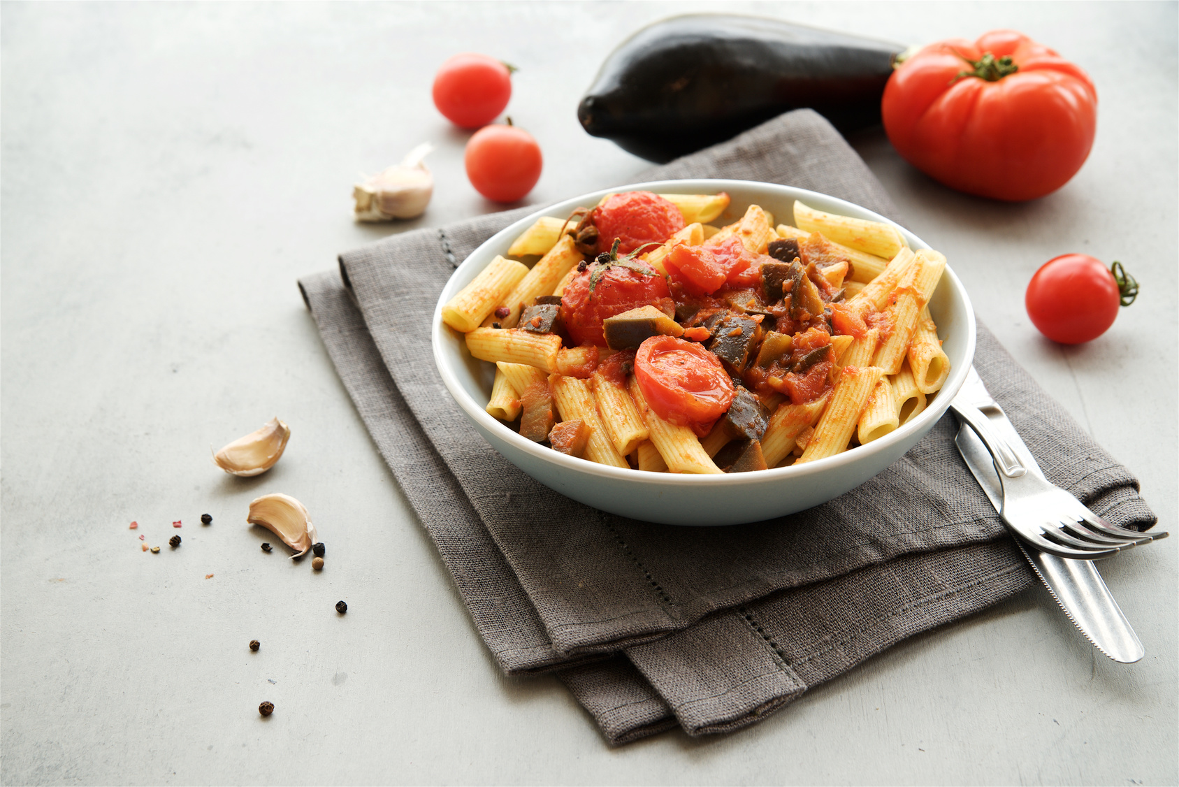 Piatto di penne con pomodoro e melazane; concept: pasta, carboidrati