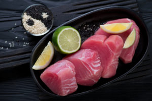 Filetto di tonno a fette con fette di lime in un piatto nero