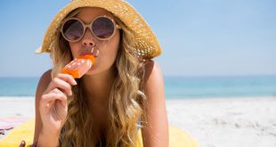 Woman eating popsicle while relaxing at beach