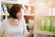 Donna consulta l'etichetta di un prodotto tra gli scaffali di un negozio o un supermercato