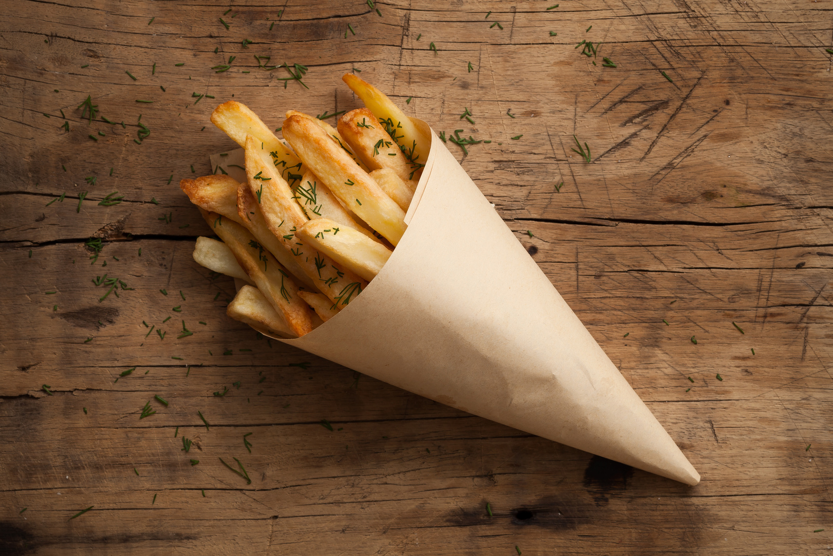 Patate fritte avvolte in un cono di carta paglia; concept: acrilammide