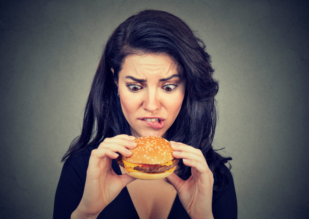 Young woman craving a tasty Hamburger .