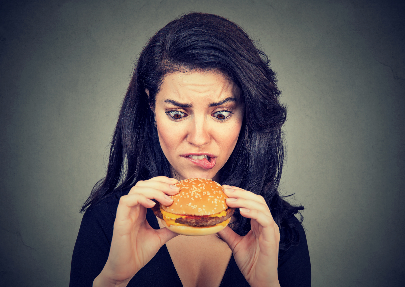 Young woman craving a tasty burger .