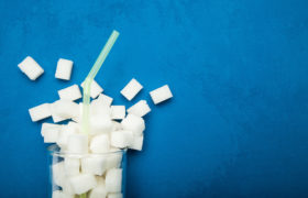 Spilled sugar from a glass on a blue background. Giant sugar concentration in everyday beverages.