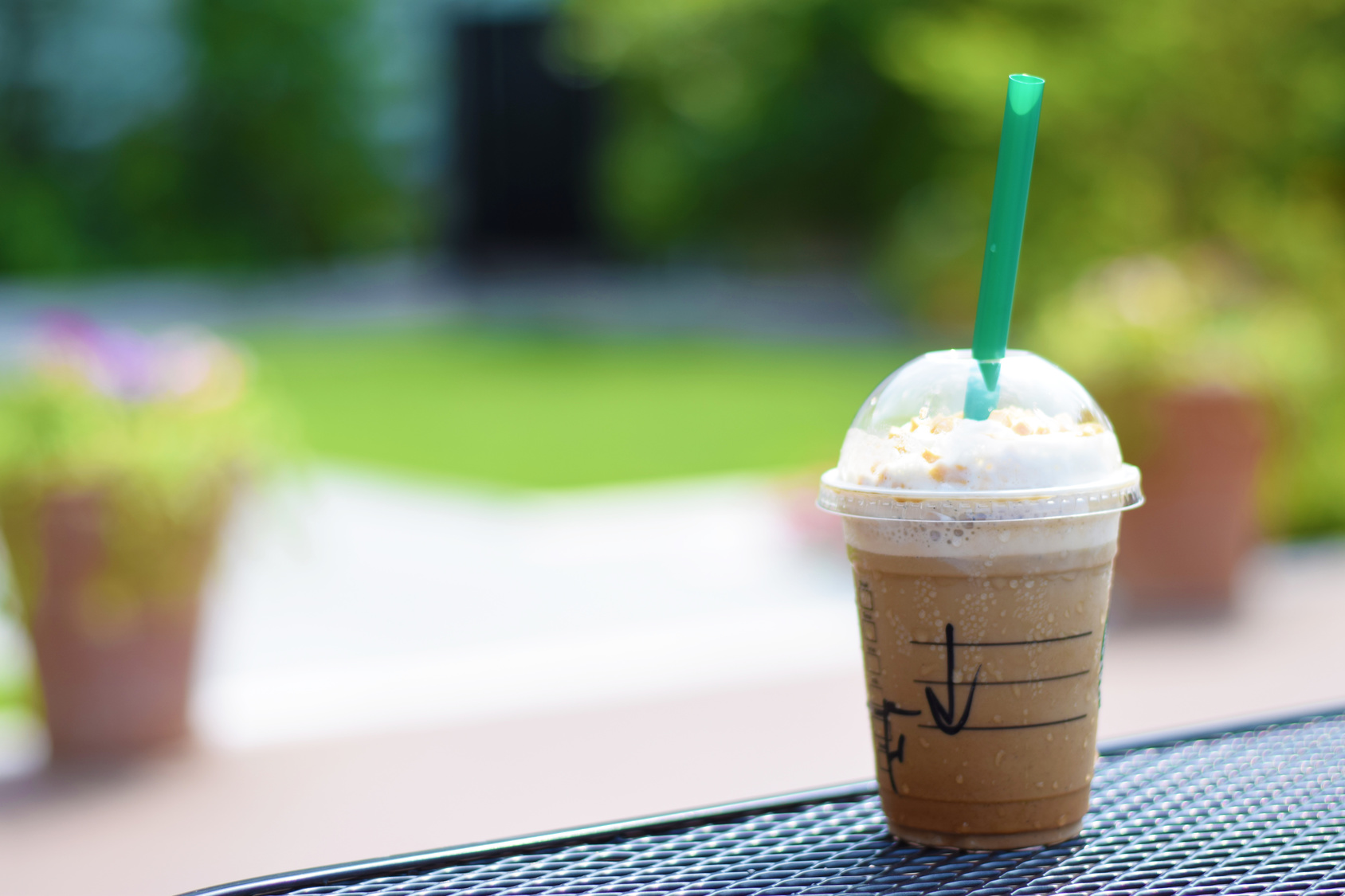Bicchiere di plastica trasparente con coperchio e cannuccia che contiene bevanda al caffè; concept: Starbucks