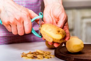 Una persona sbuccia una patata con un pelapatate