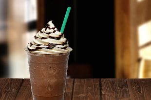 Frappuccino in takeaway cup on wooden table isolated on cafe background