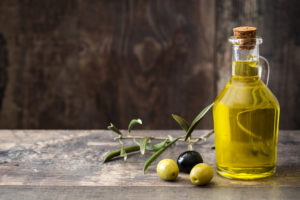 Virgin olive oil in a crystal bottle on wooden background.Copyspace