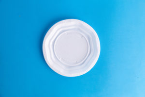 Piatto di plastica bianco su sfondo azzurro