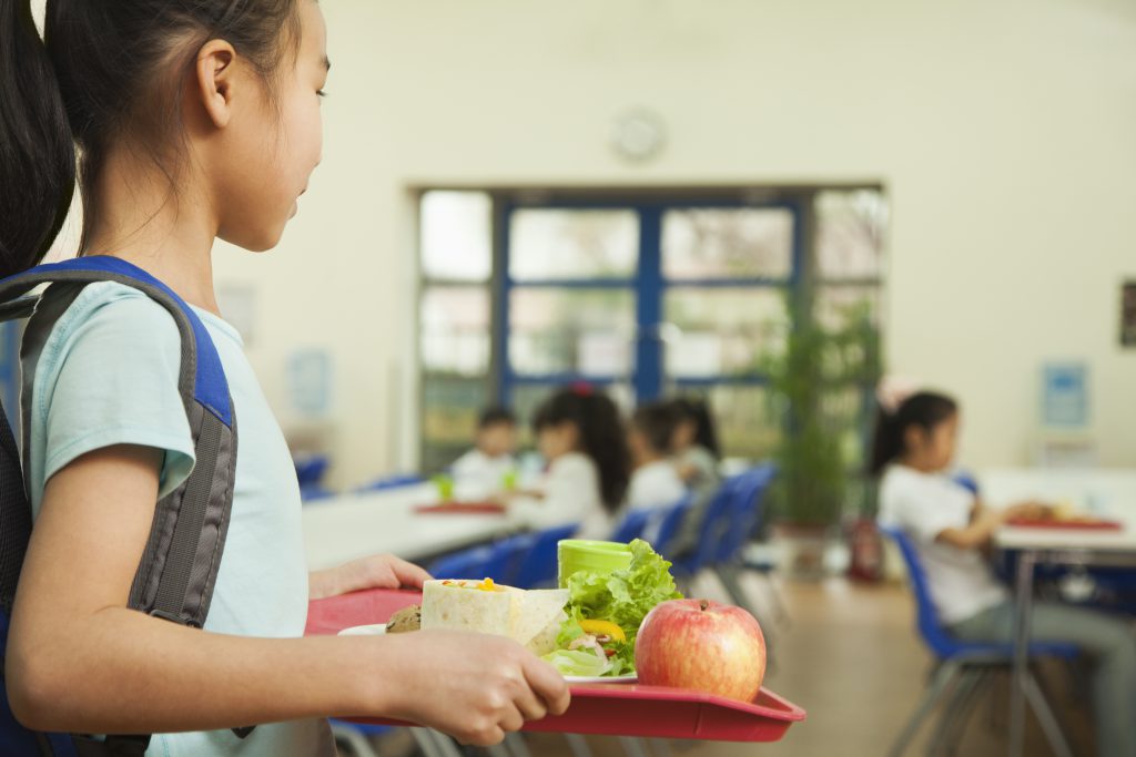 School girl holding food tray in school cafeteria