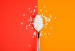 Sugar-replacing tablets spoon on orange and red background