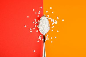 Sugar-replacing tablets spoon on orange and red background