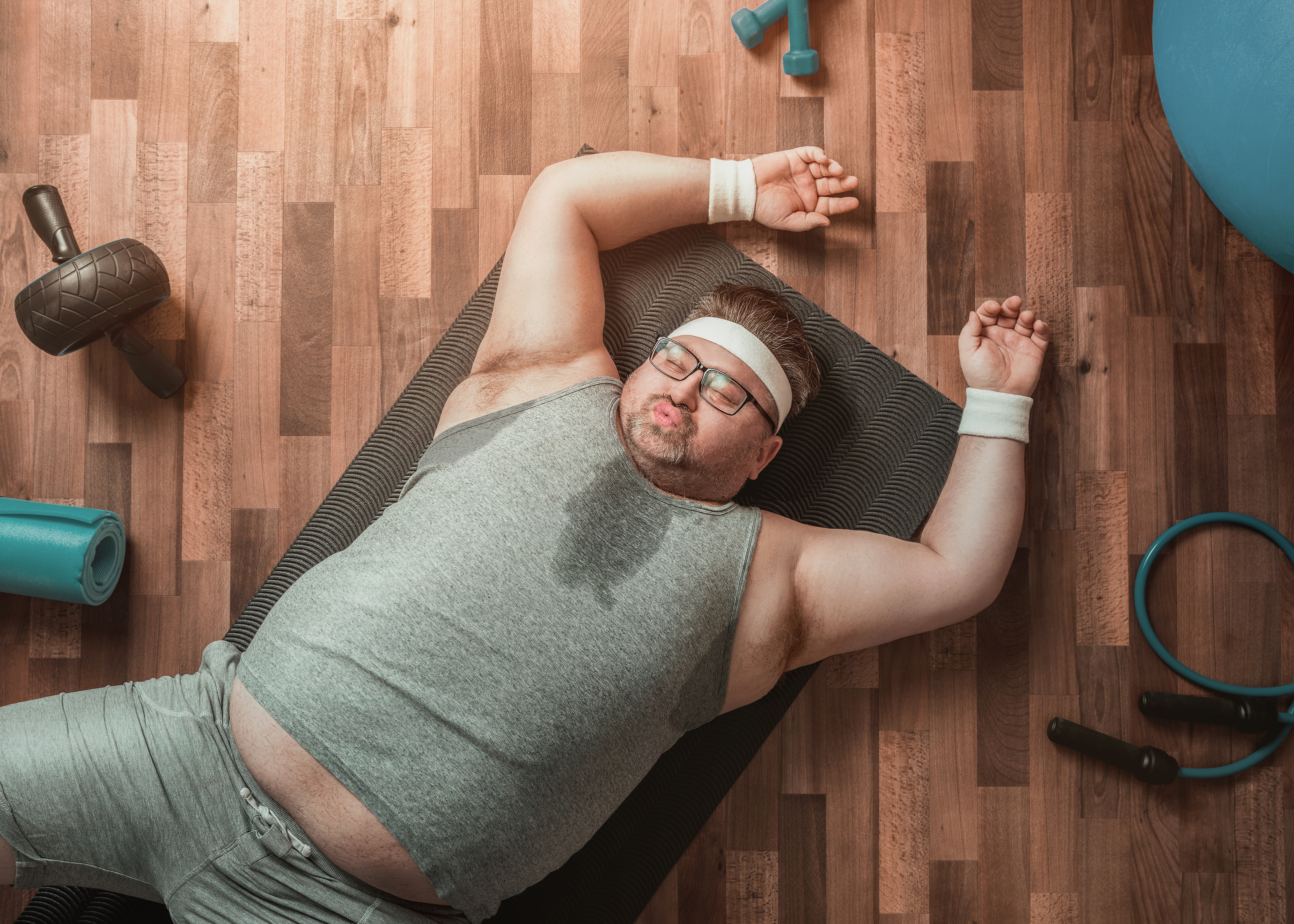 Uomo sovrappeso sudato steso su un tappetino da ginnastica; concept: sport, attività fisica