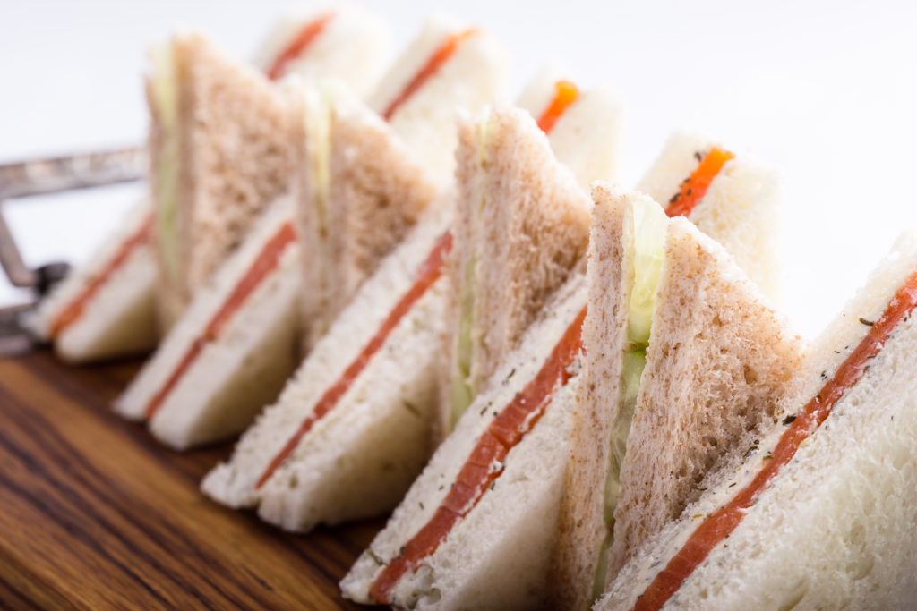 Tramezzini o sandwich tipici inglesi con salmone, formaggio e cetrioli; concept: ora del tè, pane