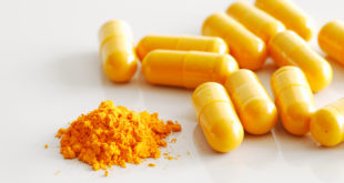 A handful of turmeric capsules with the contents of one spilled