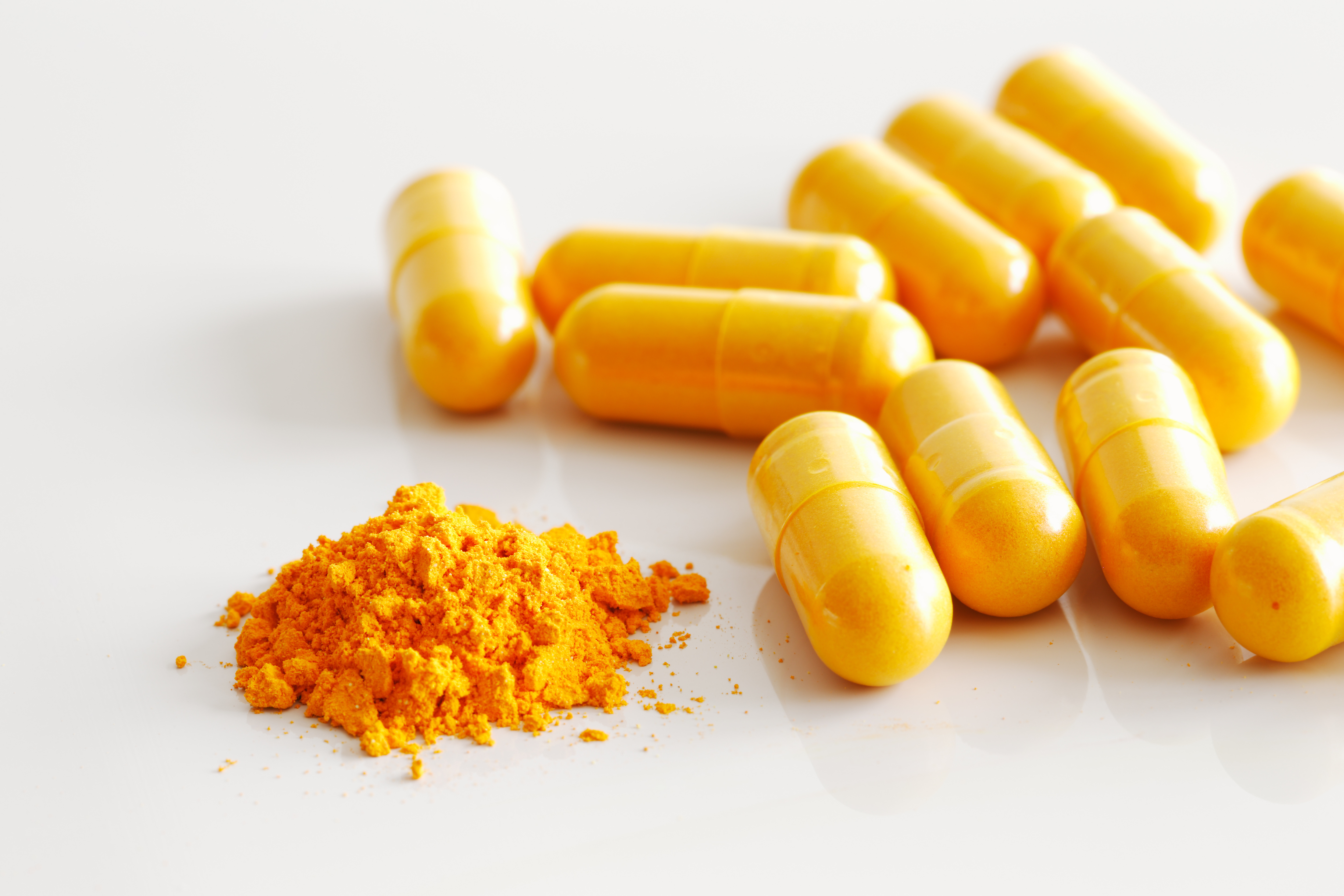 curcumina, A handful of turmeric capsules with the contents of one spilled
