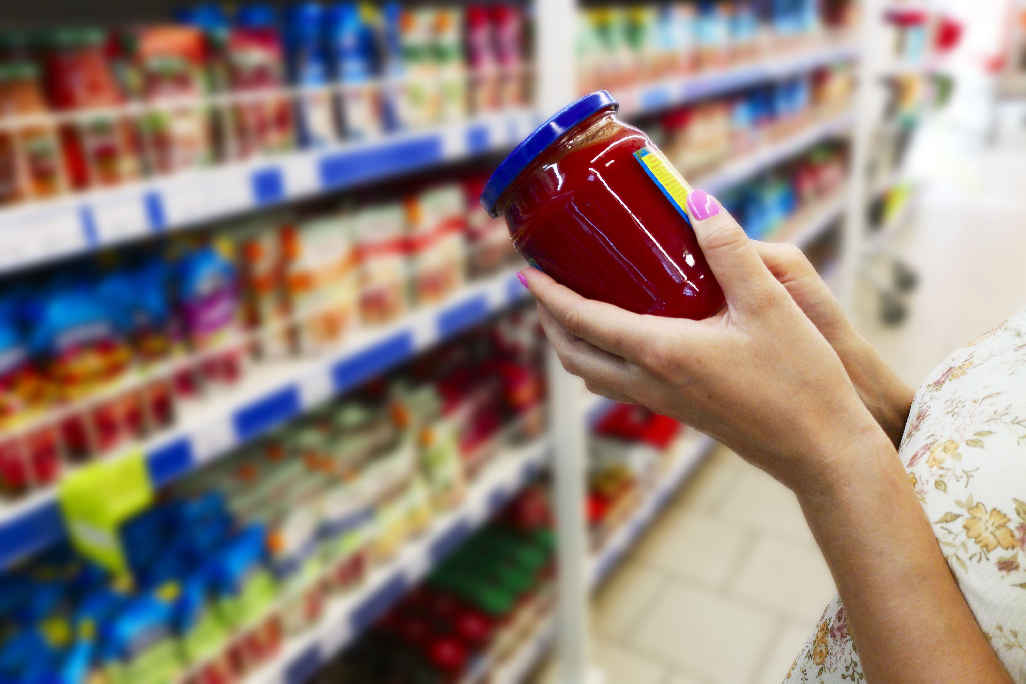 Glass jar of sauce in the hands of the buyer. Sauce in the hands of the buyer at the grocery store