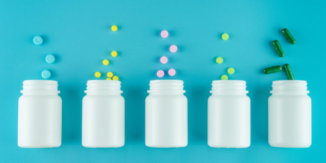 Medicines, supplements and drugs in a bottle on blue background integratori