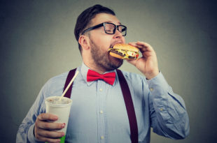 luce, Overweight business man eating with appetite a burger holding a can of soda drink