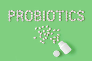 Probiotics word made of pills on green background. Flat lay, top view, free copy space.