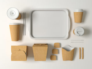 Packaging in carta per alimenti: scatole e bicchieri disposti intorno a un vassoio