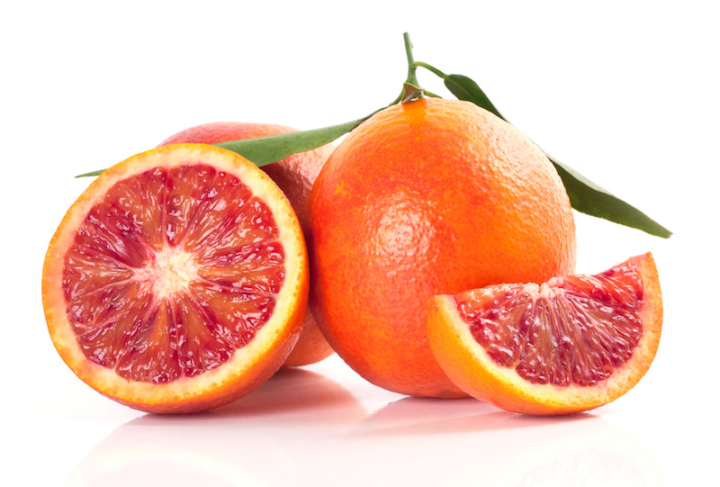 marmellata, due arance intere più una tagliata, su piano bianco neutro
