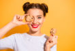 Close up photo of charming lovely hipster playing with cakes pies candies in kitchen preparing for birthday dressed in white woolen pullover isolated over colorful background