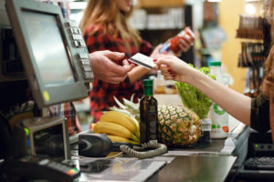 Una cassiera porge una carta di credito a una persona; concept: cassa del supermercato