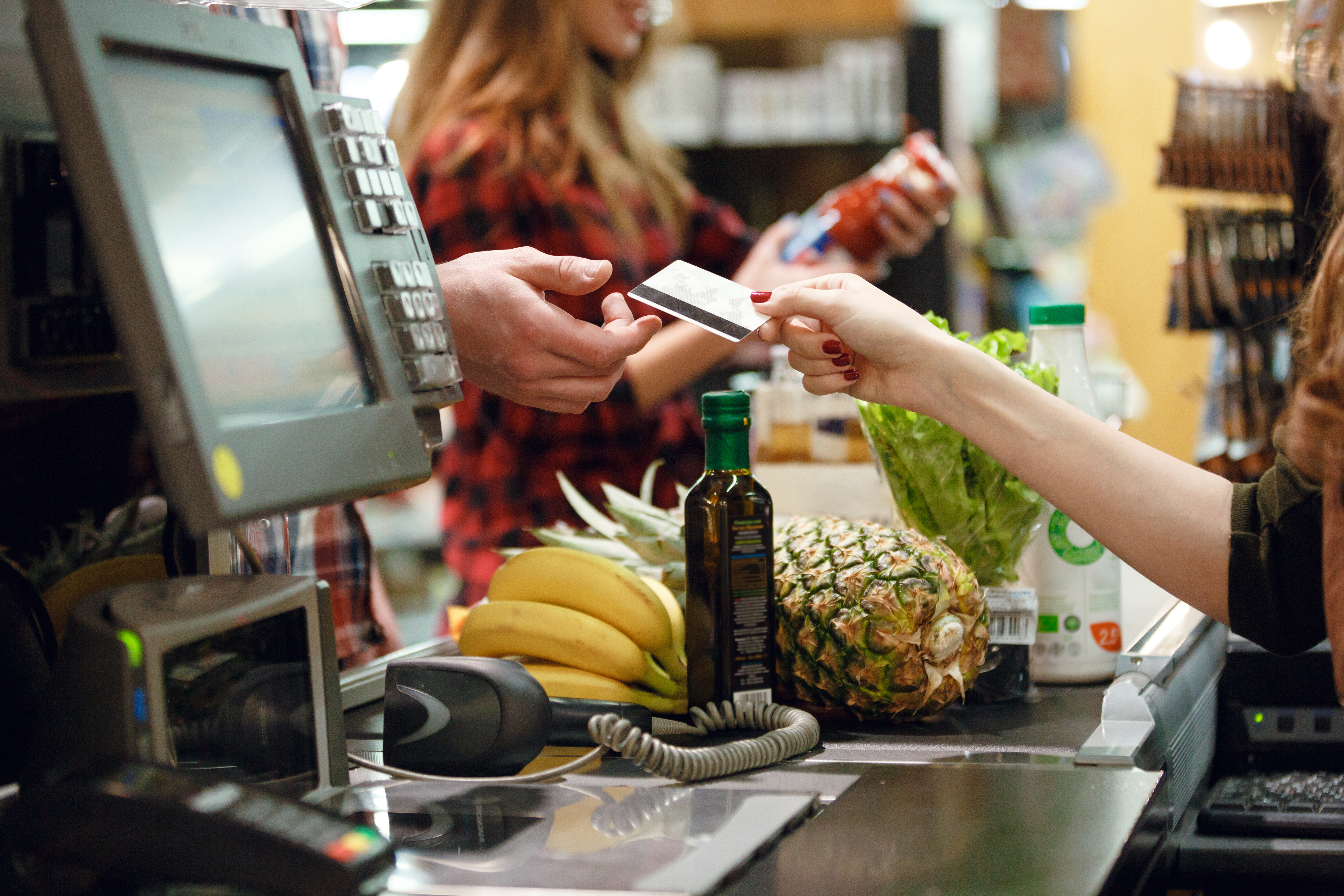 Una cassiera porge una carta di credito a una persona; concept: cassa del supermercato