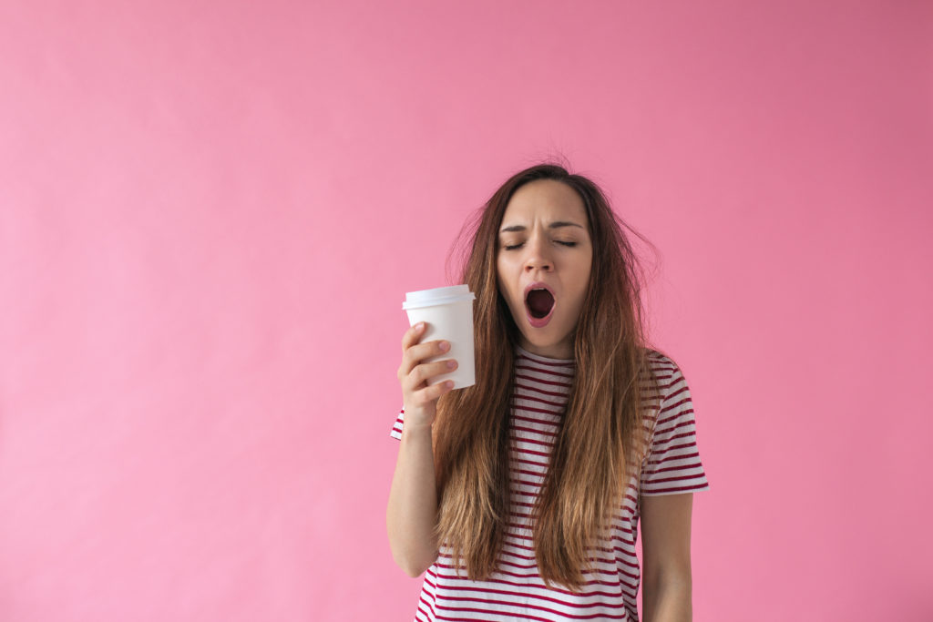 Girl with coffee is yawning.