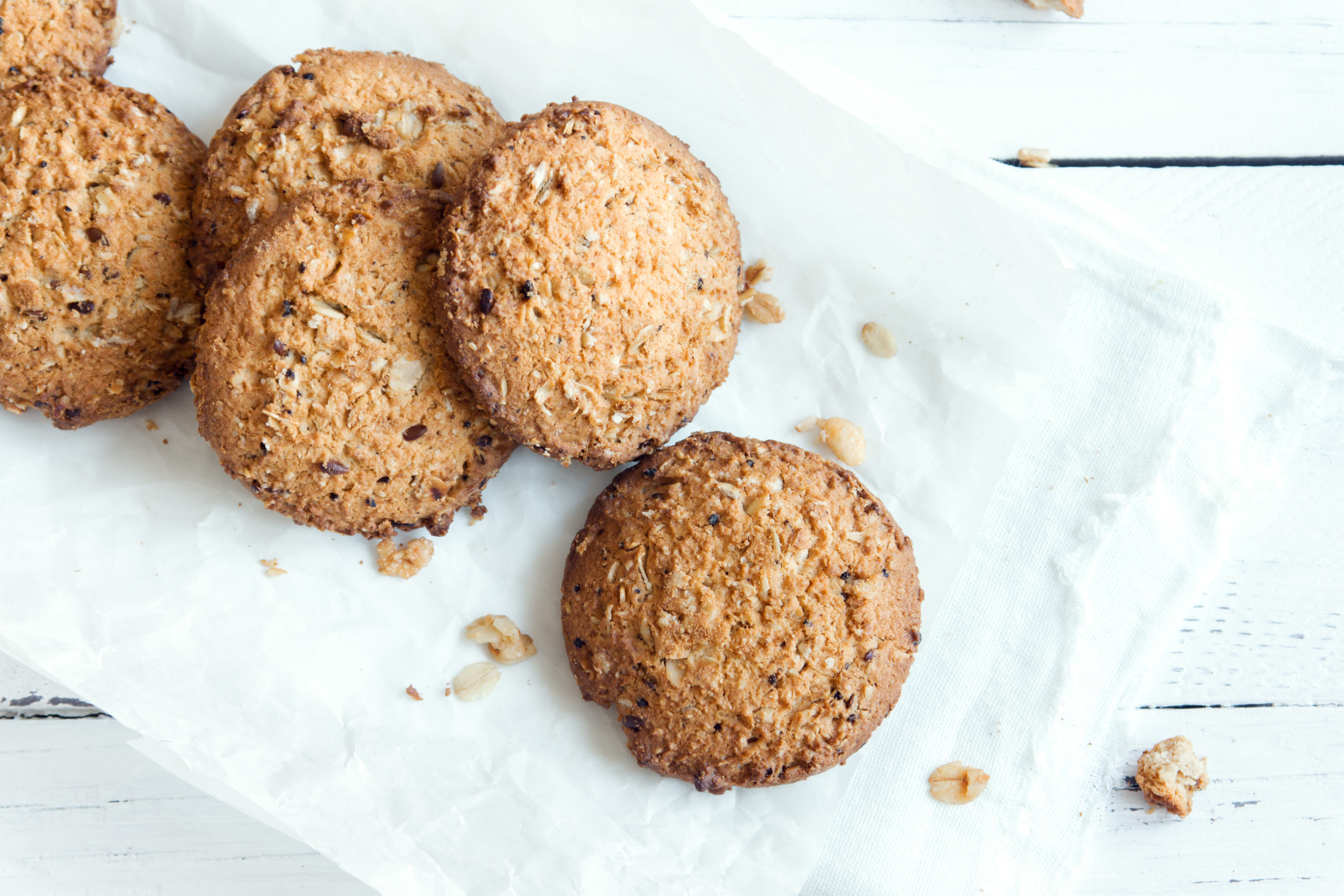 Biscotti di farina d'avena fatti in casa con semi di lino e sesamo su tavolo di legno bianco, copia spazio. Biscotti d'avena vegani sani.