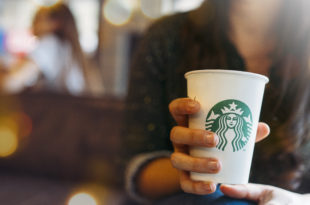 New York, USA - November 5, 2019 : Close up of a Woman drinking a tall Starbucks coffee in starbucks coffee shop with carrot cake. ManuPadilla - stock.adobe.com