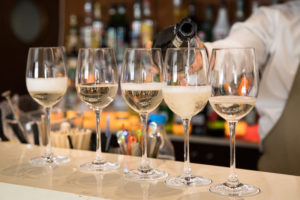 Calici di vino bianco, spumante, prosecco o champagne allineati su un bancone