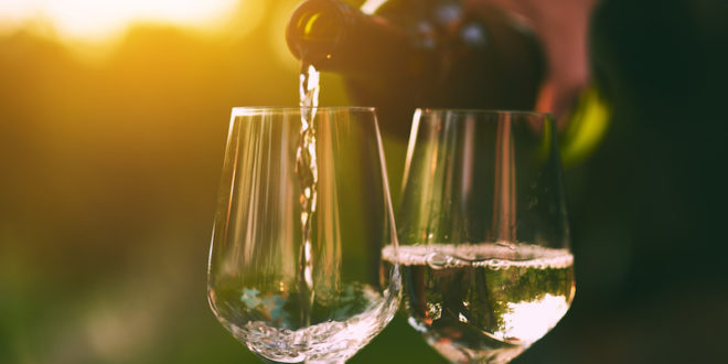 vini, due calici di vino bianco con bottiglia in atto di versare e il sole sullo sfondo, concept: alcol