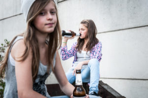 Due ragazze adolescenti bevono birra all'aperto dalle bottiglie